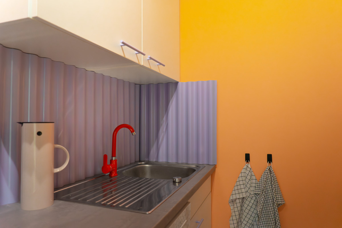 Teeküche mit Wellenspritzschutz und rotem Wasserhahn