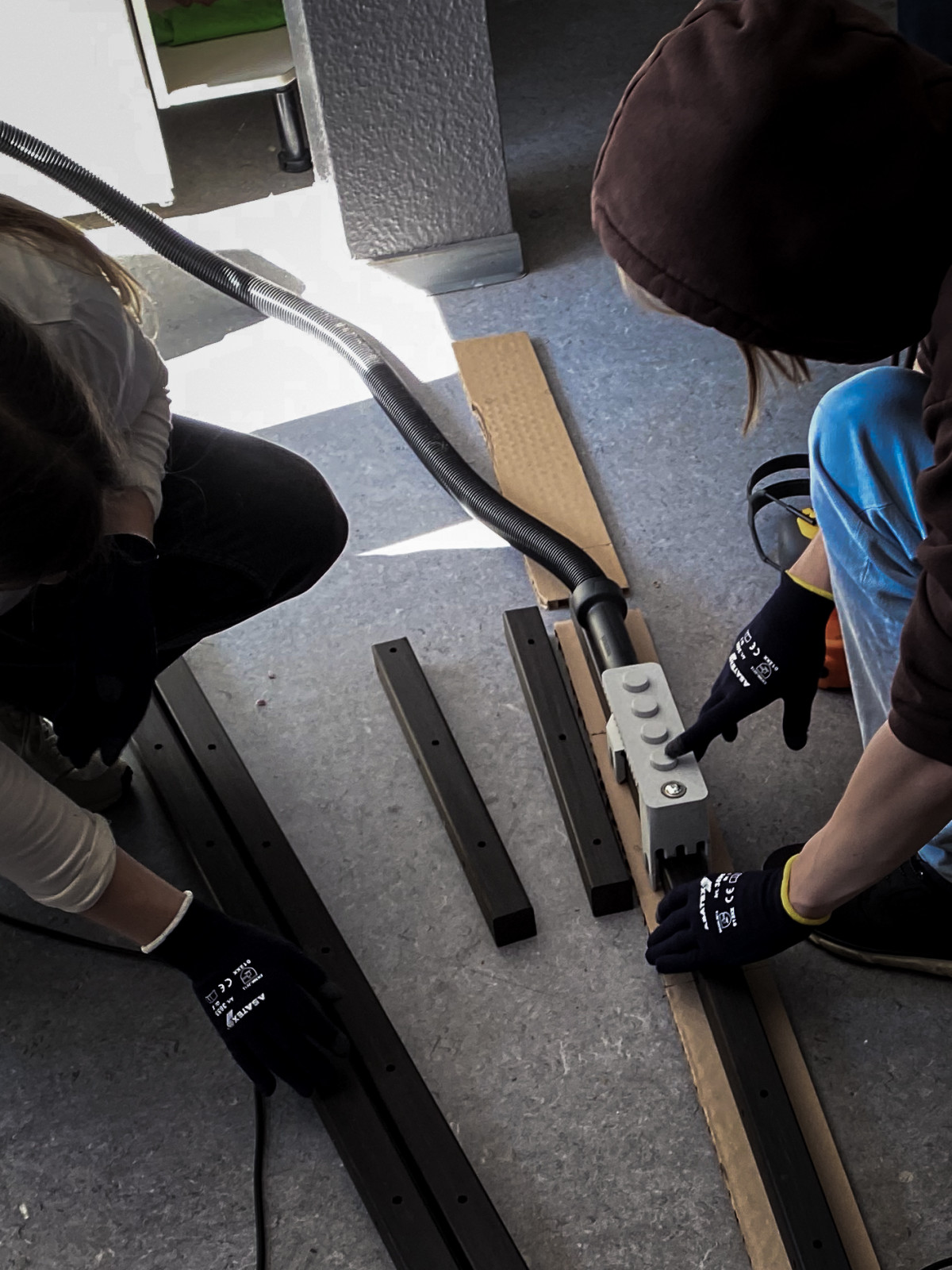 Das Multitool angeschlossen mit dem Staubsauger auf dem Holz