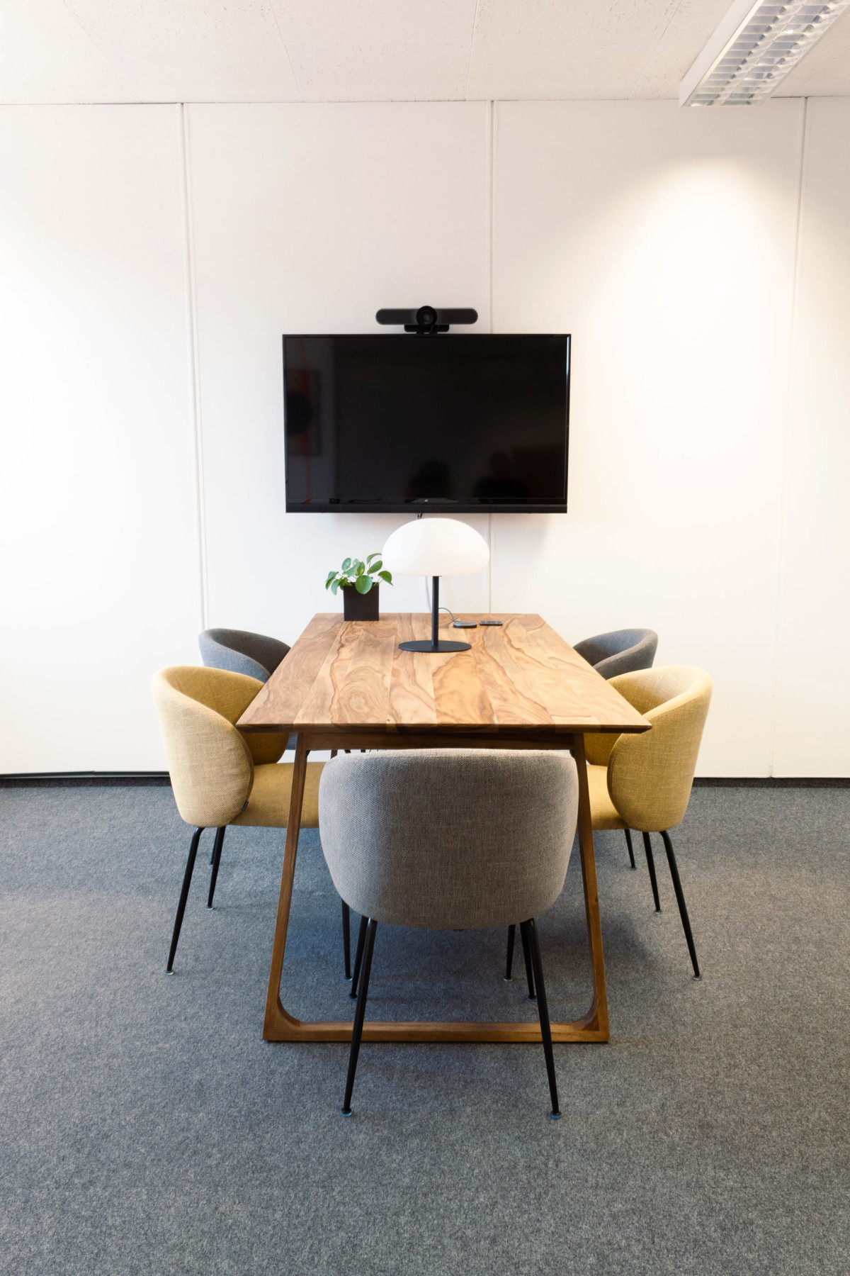Großer Meeting-Tisch mit farbigen Stühlen und Monitor